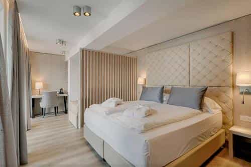 Modern hotel bedroom with large bed, quilted headboard, desk area, and light wood accents