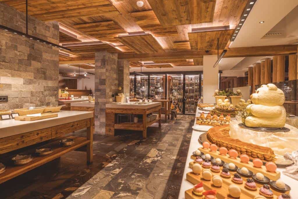 Dessert buffet with butter sculpture, pastries, and macarons in a room with wood ceilings.