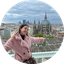 Woman in pink coat overlooking city skyline with large domed church.