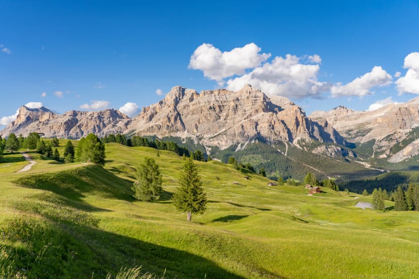 nice and active senior woman riding her electric mountain bike on the Pralongia Plateau in the Alta Badia Dolomites with awesome Sasso die Santa Cruce summit in Backg, South Tirol and Trentino, Italy