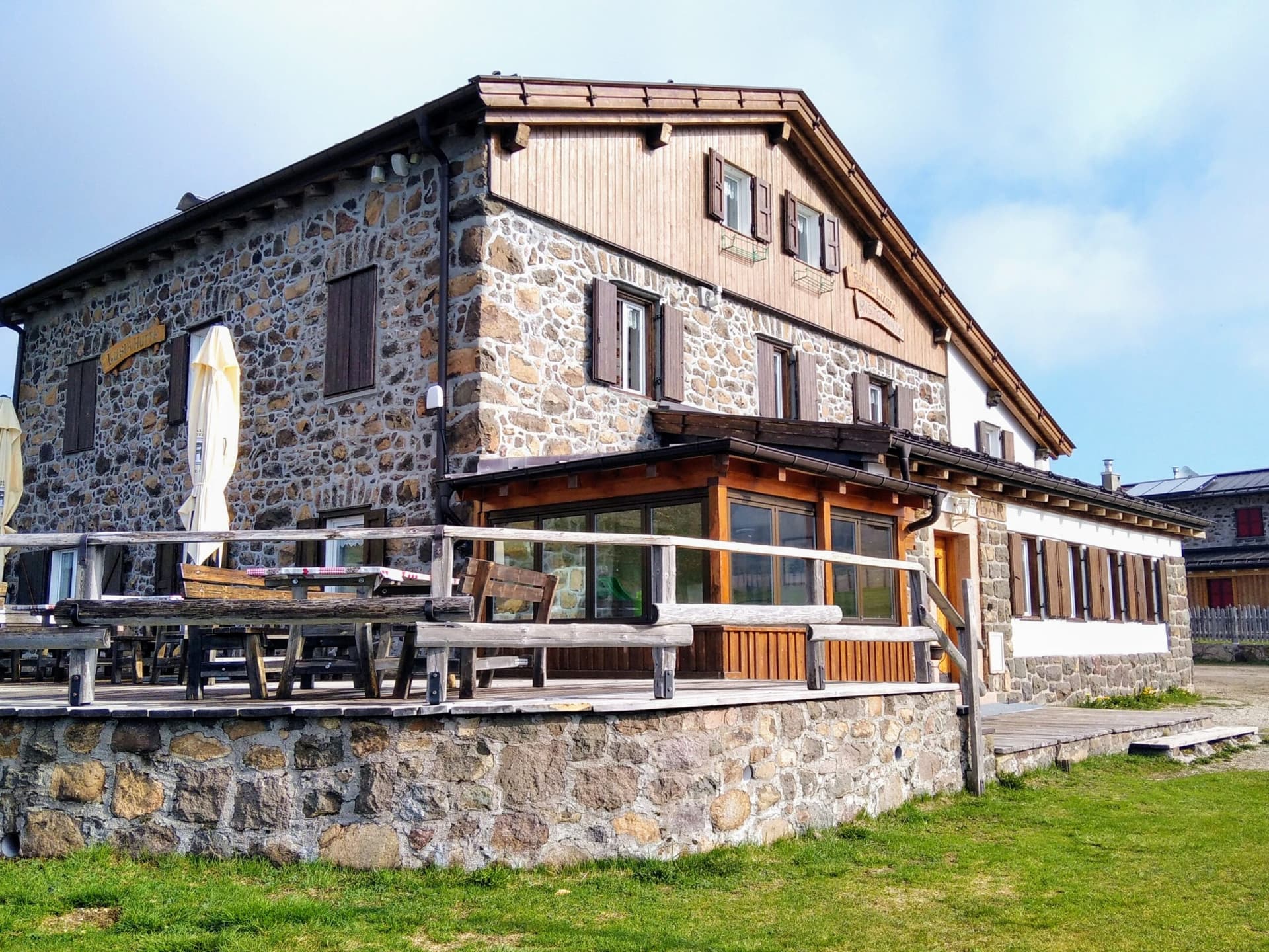 Rifugio Lusia stone mountain hut with outdoor wooden terrace in the Dolomites.