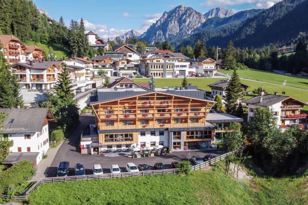 Hotel building with wooden balconies in alpine village with mountains
